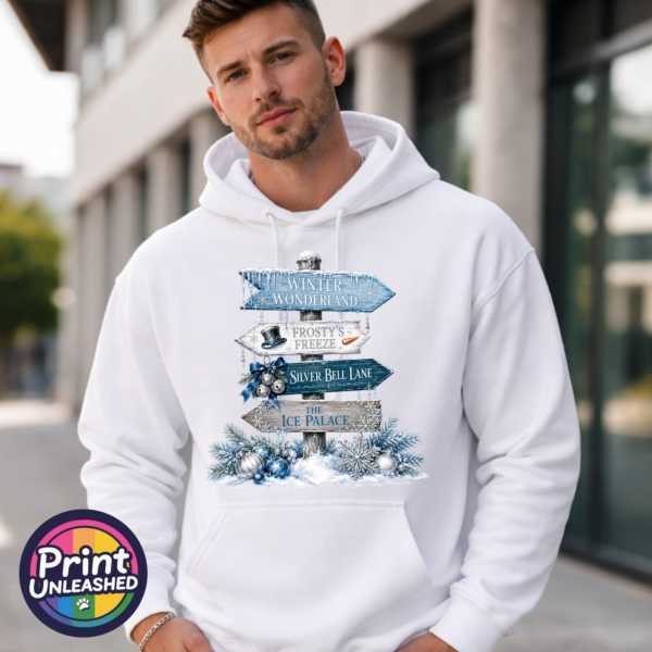 Winter Wonderland hoodie male Snow-covered signpost pointing to Winter Wonderland, Frosty’s Freeze, Silver Bell Lane and the Ice Palace, with blue and silver decorations, printed on a white unisex hoodie male model - Print Unleashed