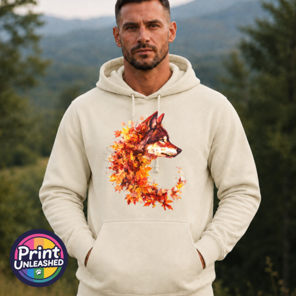 Wolf in profile with a golden eye and fur blending into red, orange and golden autumn leaves on a softstyle hoodie model - Print Unleashed