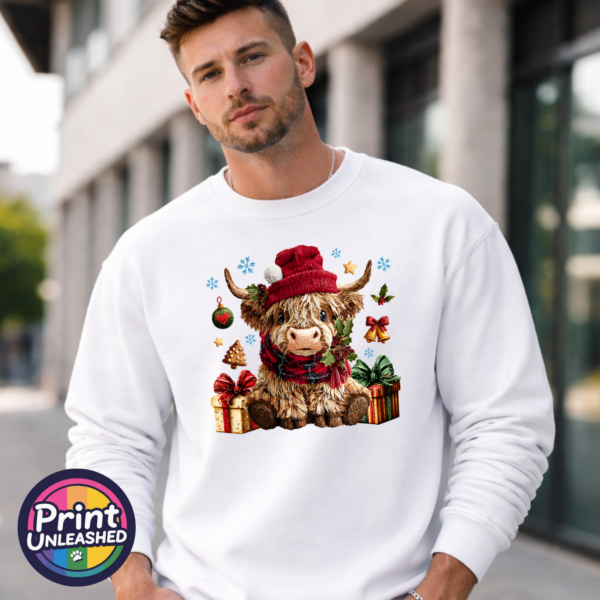 Yarn-style Highland cow wearing a red hat and checked scarf, surrounded by presents, holly, bells and snowflakes, printed on a white unisex sweatshirt male model - Print Unleashed