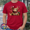 Yarn-style Highland cow wearing a red hat and checked scarf, surrounded by presents, holly, bells and snowflakes, printed on a cherry red premium unisex T-shirt male model - Print Unleashed