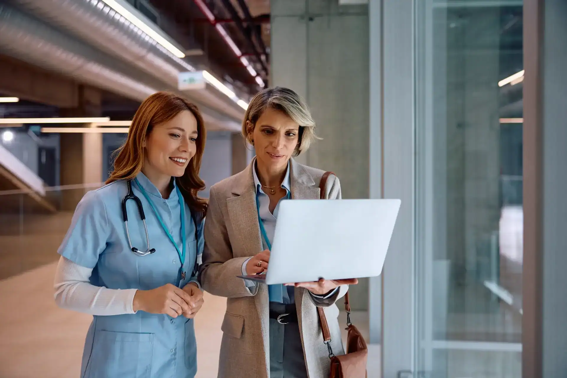 Two healthcare professionals analyzing information on a laptop in a modern hospital.