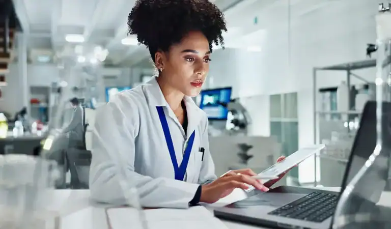 Medical professional analyzing data on a tablet in a hospital setting.