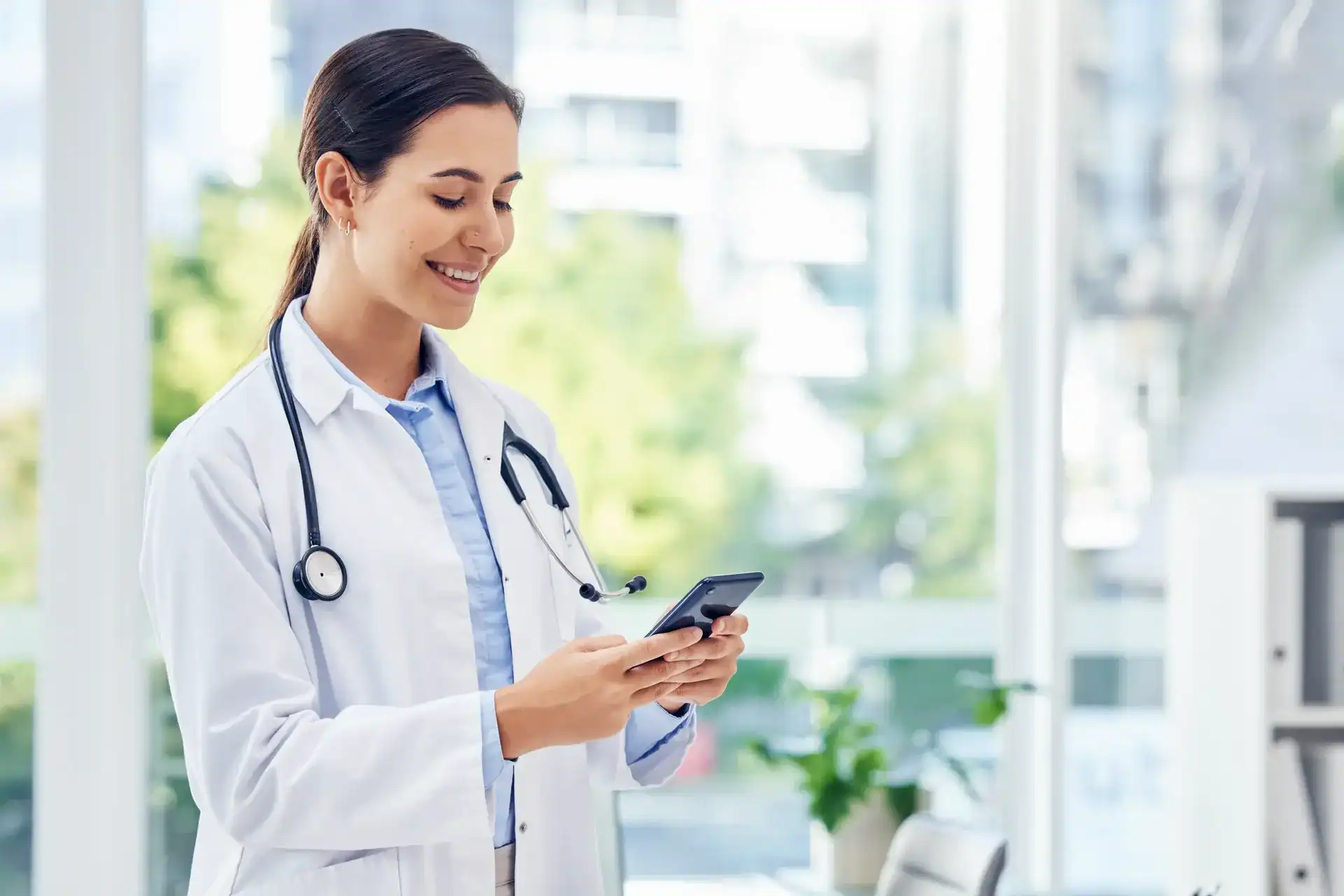 Female doctor using smartphone in modern healthcare facility.