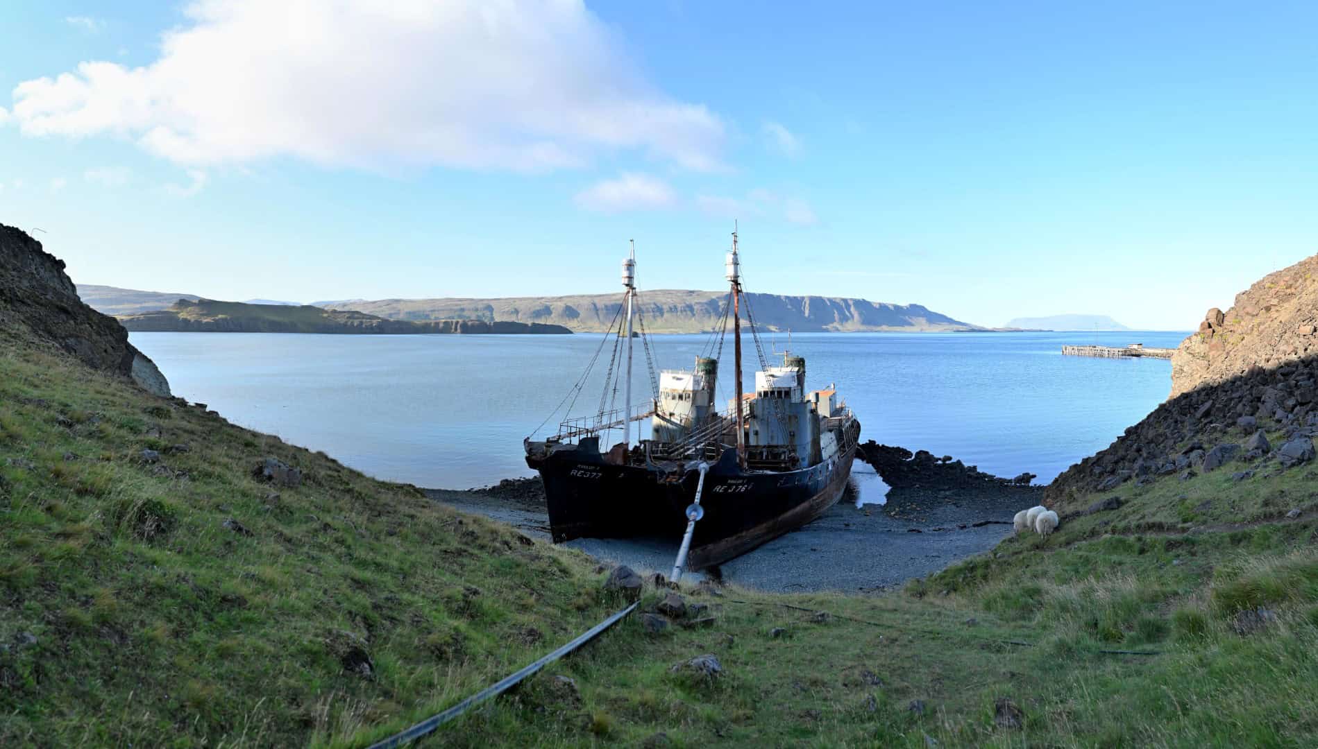 Scenic view of a ship grounded on the shore in Hvalfjörður with Reykjavík in the background, showcas.