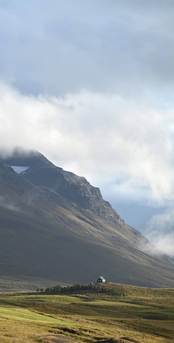 Scenic Icelandic landscape with mountains and a small house.