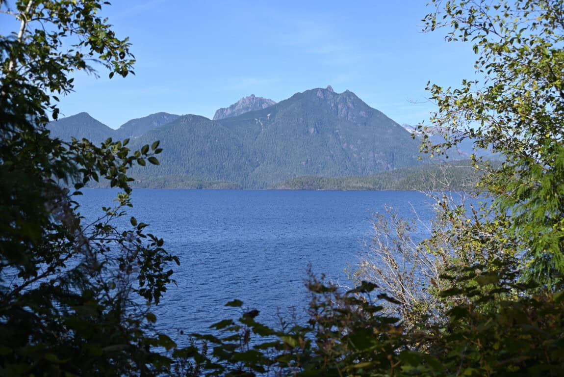 Beautiful mountain landscape over a calm lake with trees in foreground.