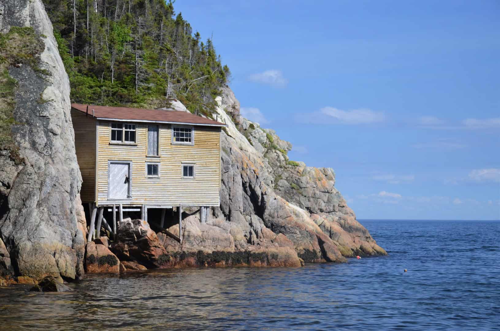 Old wooden house on rocky shoreline in Newfoundland ghost town.