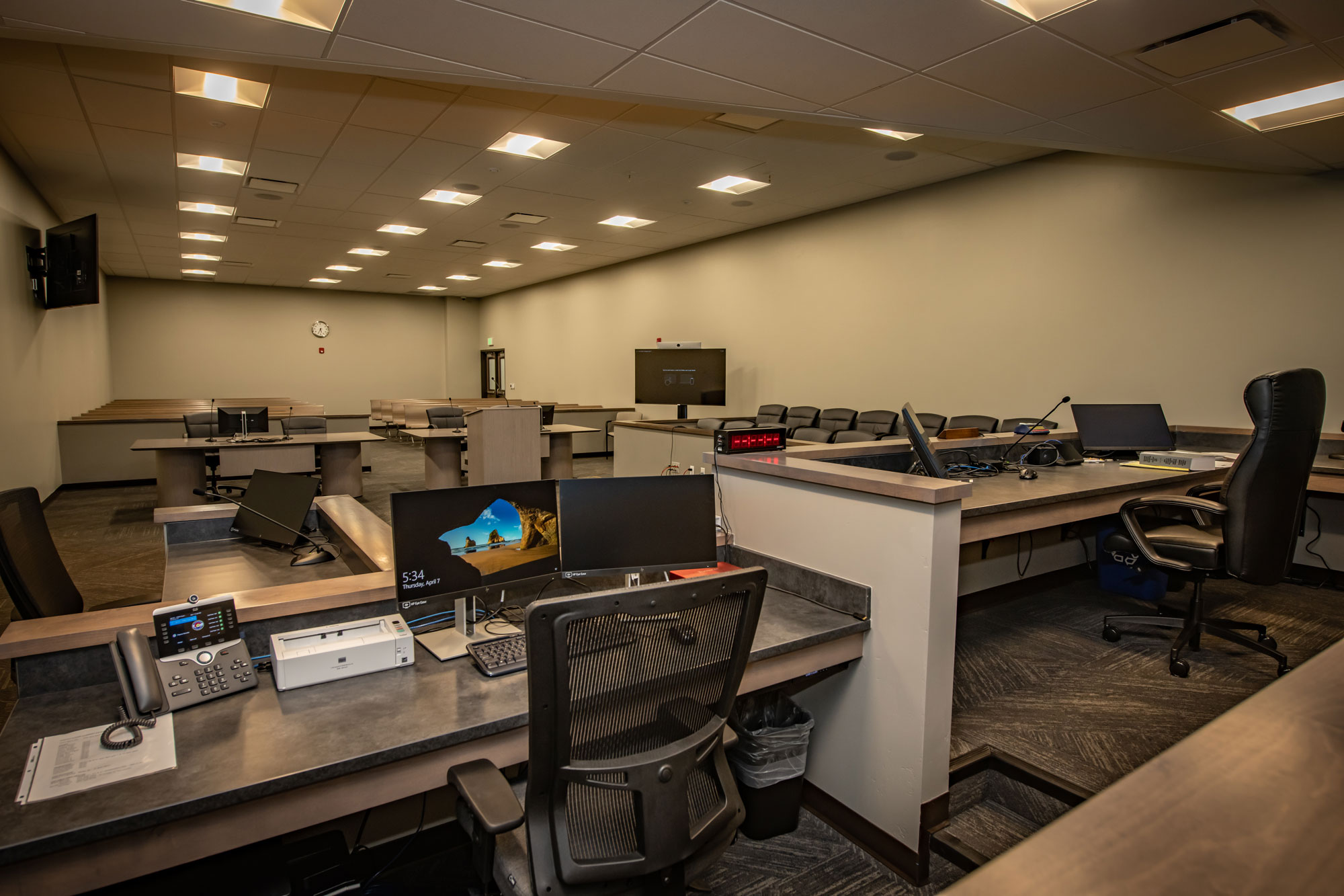 Spacious office conference room featuring workstations, presentation screen, and ergonomic chairs.