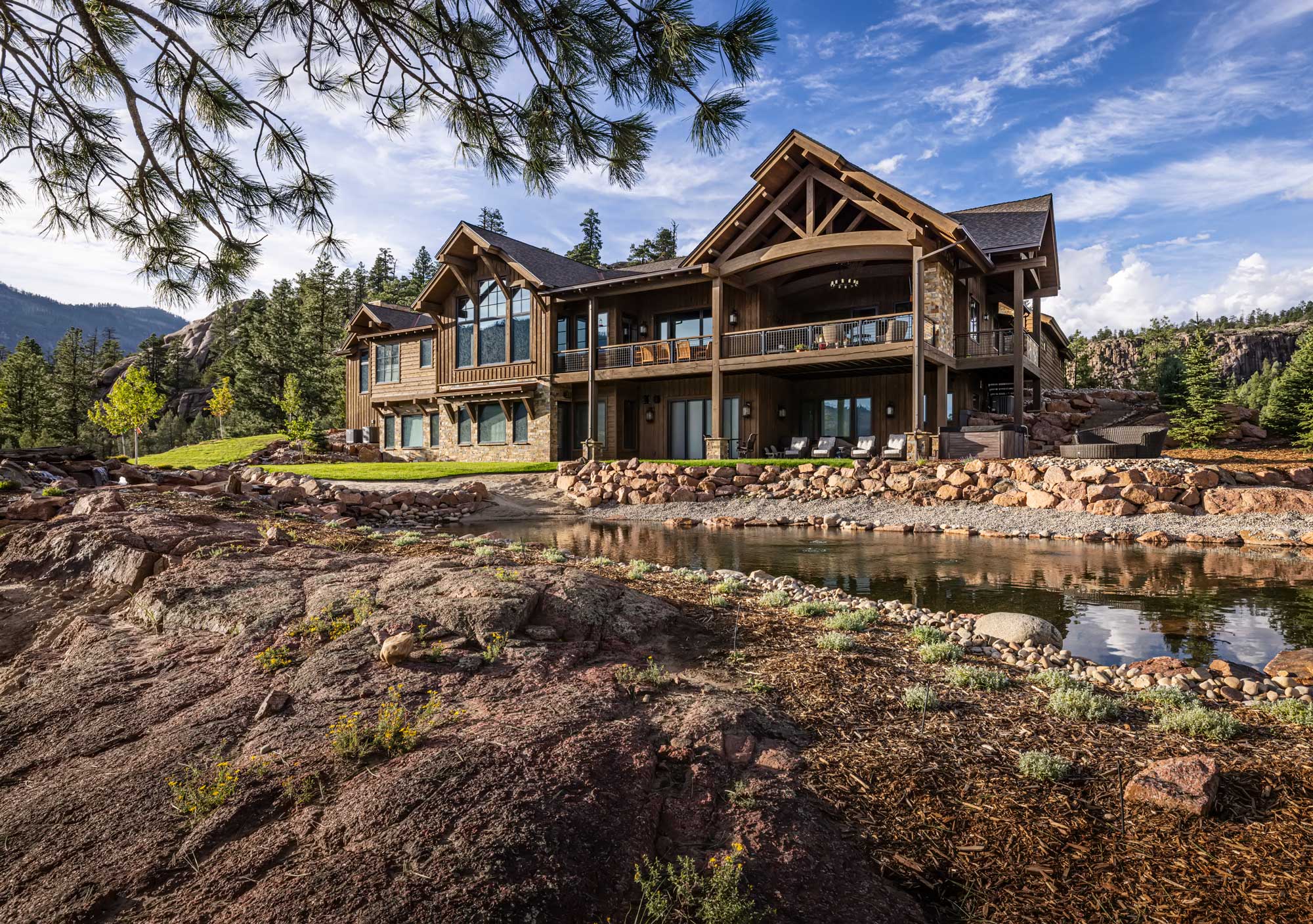 Rustic mountain estate with large windows and wooden accents in a scenic natural setting.