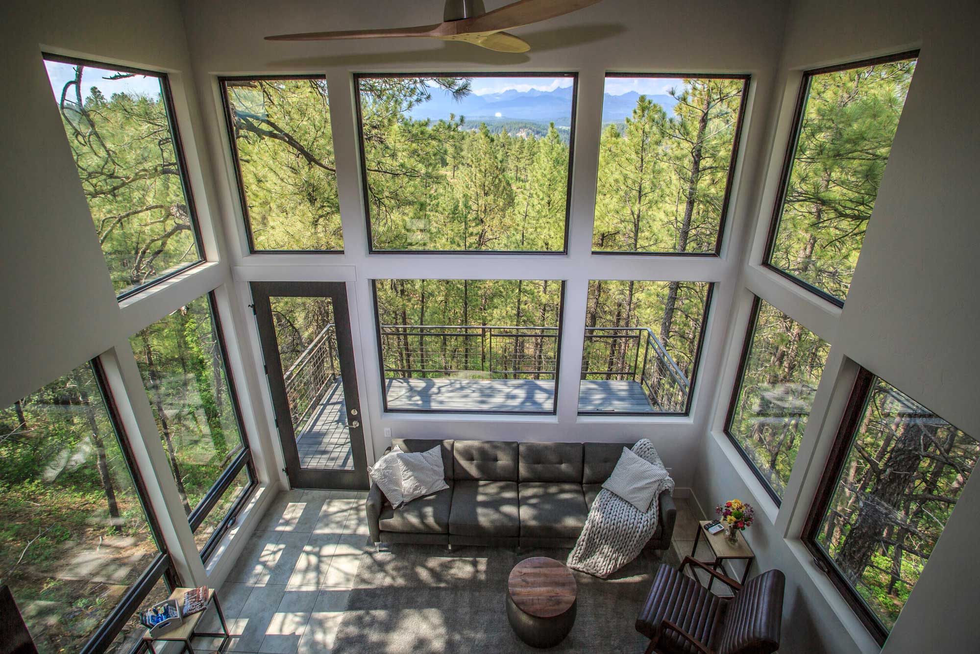 Bright living room with large windows overlooking forest scenery.