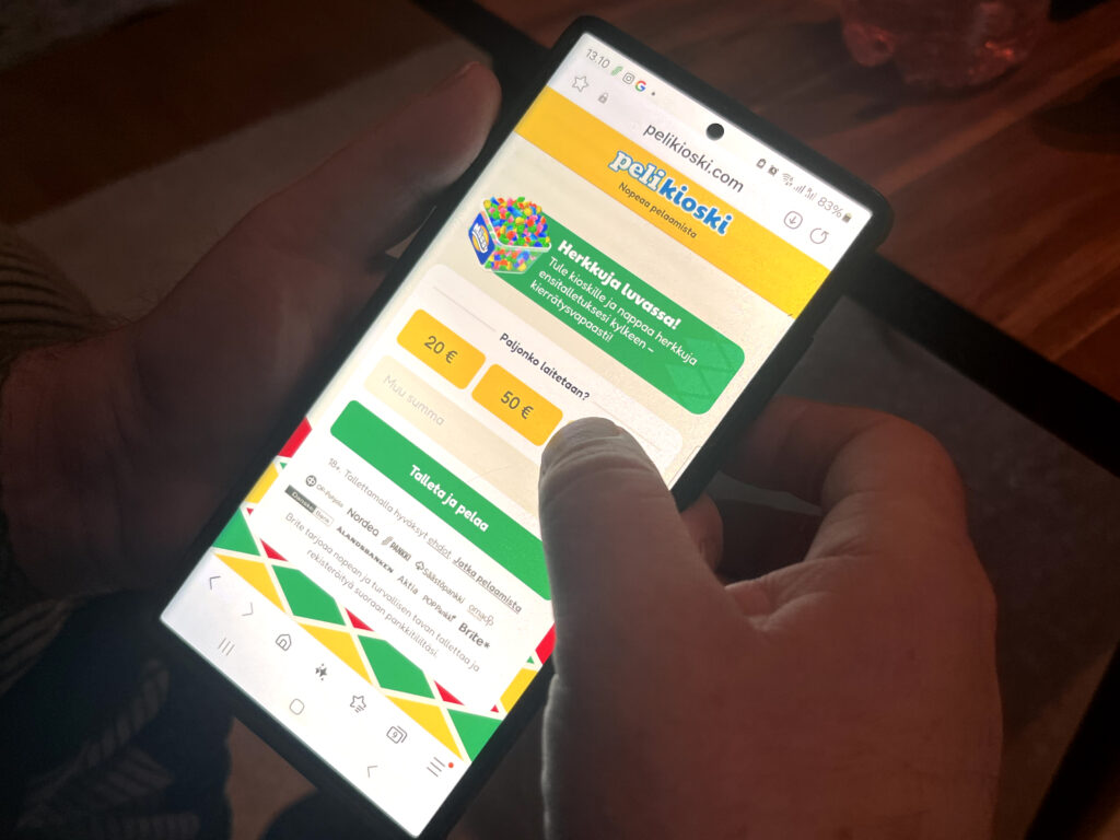 Puhelimen käyttäjän näytöllä Pelikioski nettikasino