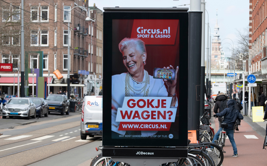 Vanhempi nainen esittelee Circus.nl nettikasinoa katumainoksessa Amsterdamissa.
