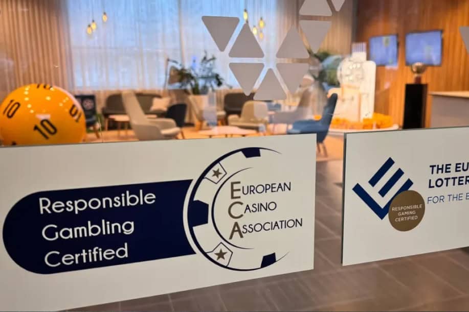 Veikkauksen toimisto lasioven takaa. Lasioevssa European Lotteries ja European Casino Association logot. Huoneessa sisällä suuri lottopallo ja televisioita.