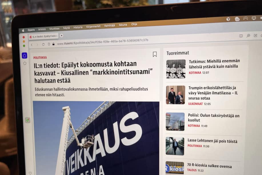 Kuvassa auki tietokonella Iltalehden verkkosivusto missä otsikko "IL:n tiedot: Epäilyt kokoomusta kohtaan kasvavat – Kiusallinen "markkinointitsunami" halutaan estää". Artikkelikuvassa asennetaan Veikkaus Arena plakaattia.