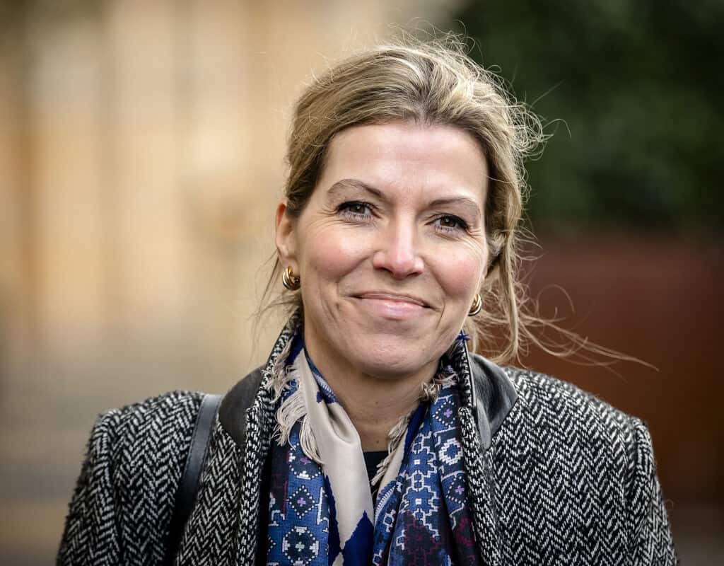 Claudia Van Bruggen hymyilee tyylikkässä takissa ja huivissa.