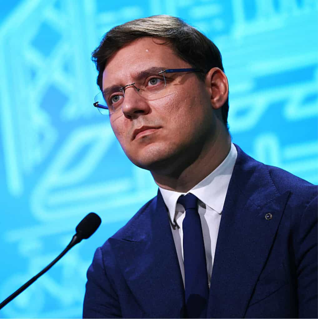 Victor Negrescu päällään puku ja edessään mikrophoni.