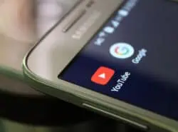 Kuvassa matkapuhelin jonka näytöllä Youtuben ja Googlen ikonit.