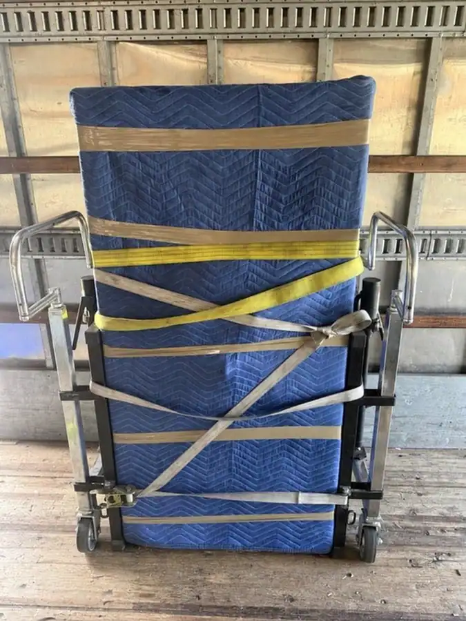 Protectively wrapped safe secured between paired moving dollies inside a Rest & Relaxation moving truck