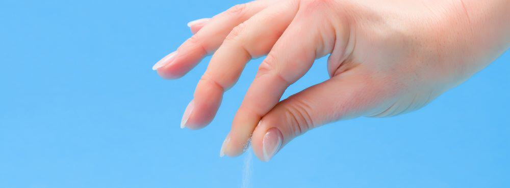 Hand sprinkling salt onto food to enhance the flavor