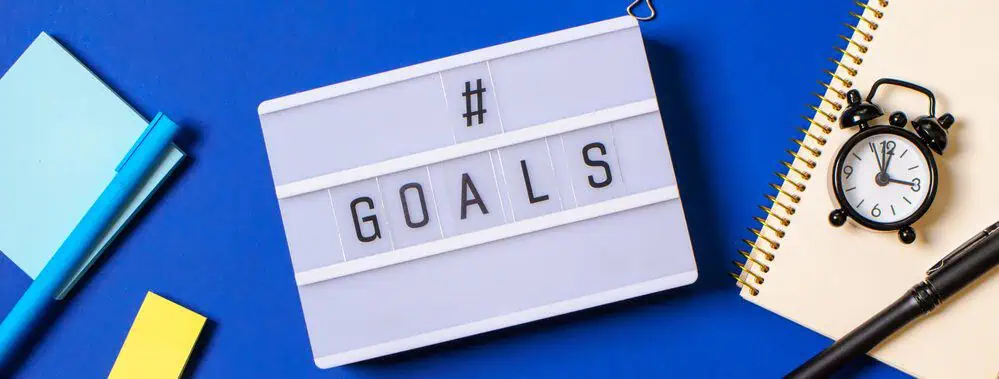 Goals The word 'goals' spelt out on a light box on a desk surrounded by work tools.