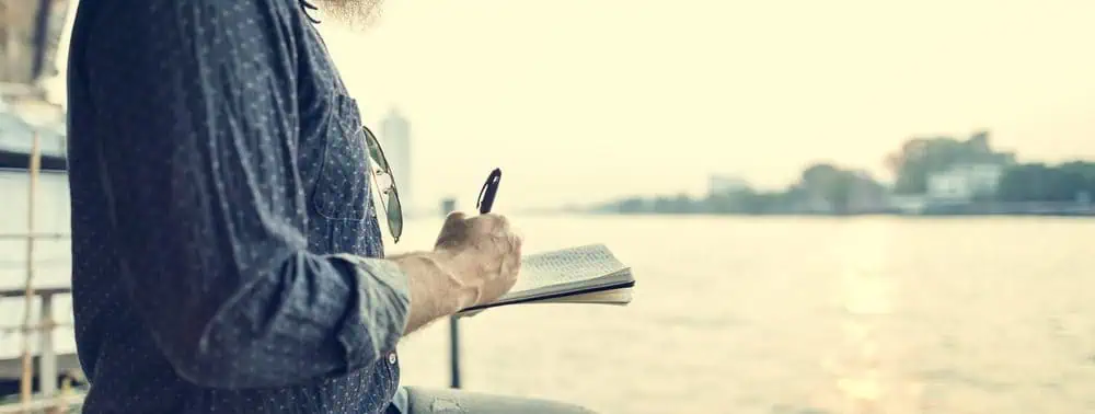 Journal Man writing in his journal against the backdrop of a beautiful view