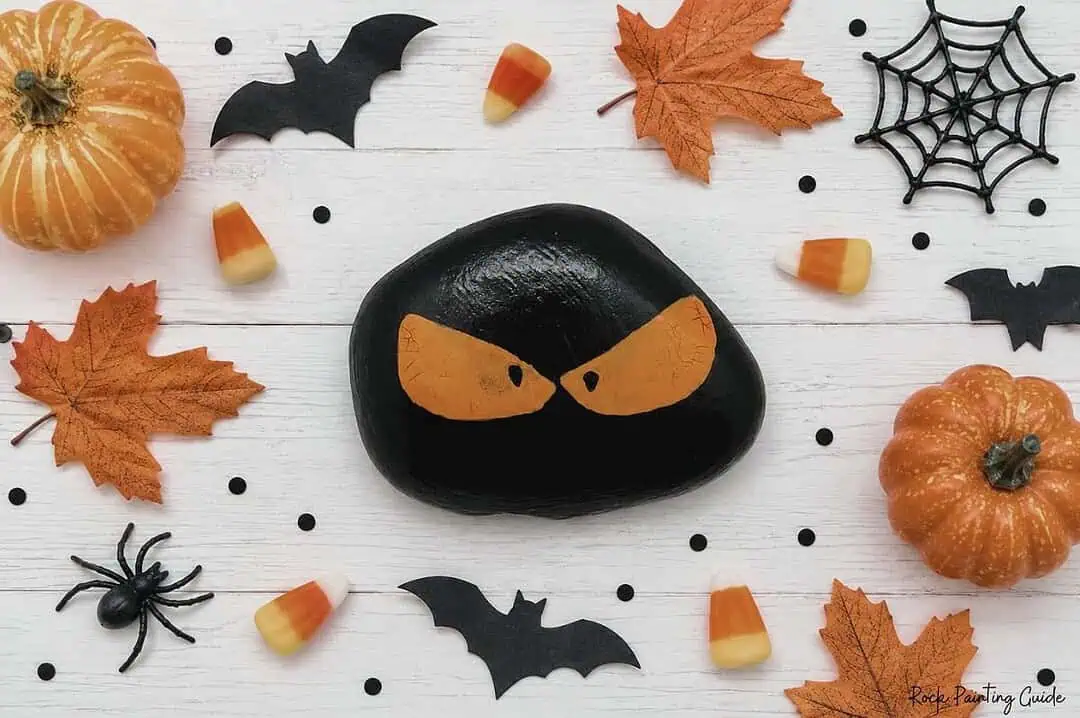 8 Easy Halloween Rock Painting Ideas for Kids 11 Black Halloween painted rock with creepy orange eyes