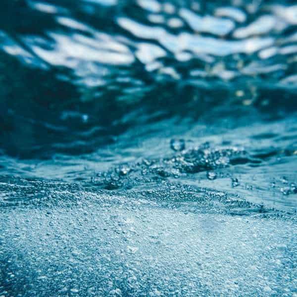 Close-up of water surface with bubbles and ripples, blue tones.