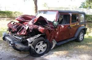 Damaged red Jeep Wrangler after a front-end collision with significant front damage.