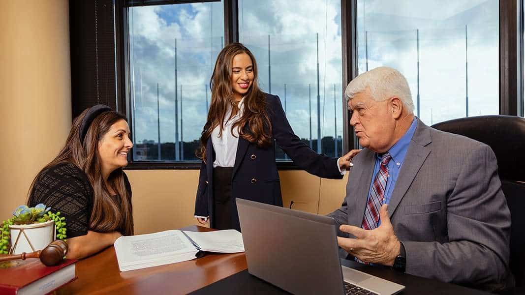 Business meeting at Romano Law Group with three professionals discussing legal matters.