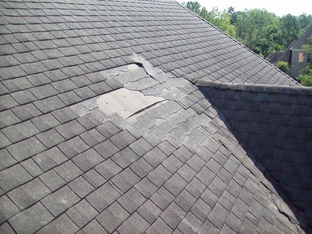 Asphalt shingle roof with wind-torn and missing shingles