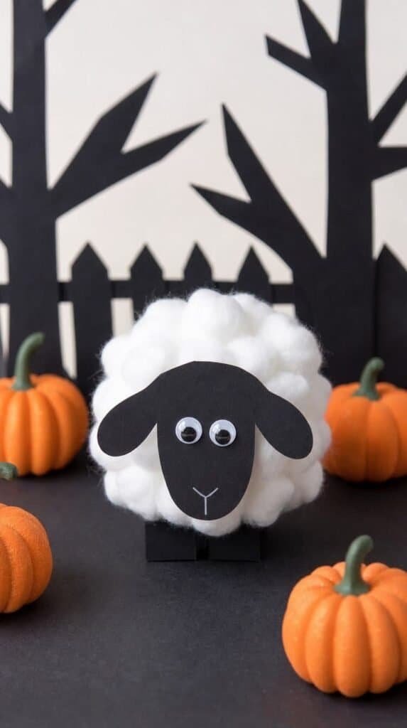 Cotton ball sheep craft in a mini pumpkin patch scene made with black paper and foam pumpkins