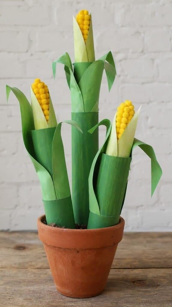 Cardboard tube corn stalk crafts painted green with paper husks in a small terracotta pot