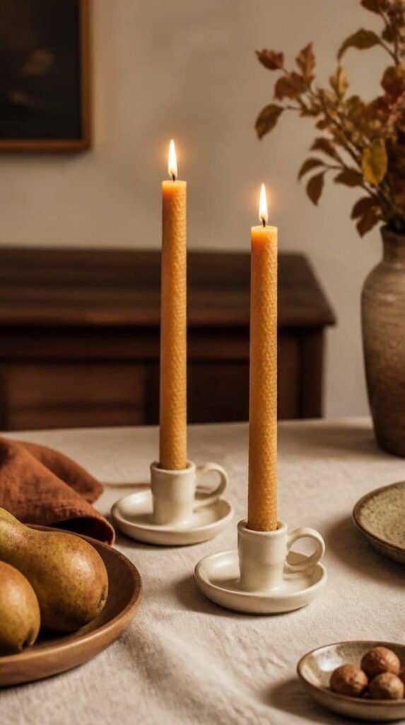 Pair of amber beeswax taper candles in ceramic holders on a linen tablecloth