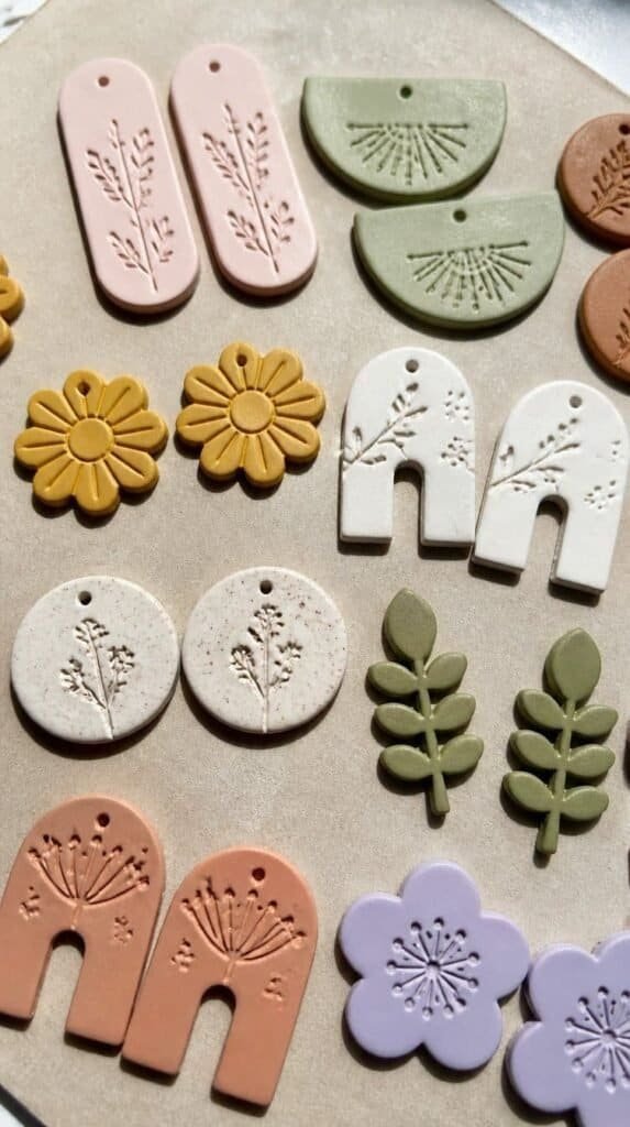Handmade stamped clay earrings drying on a craft mat