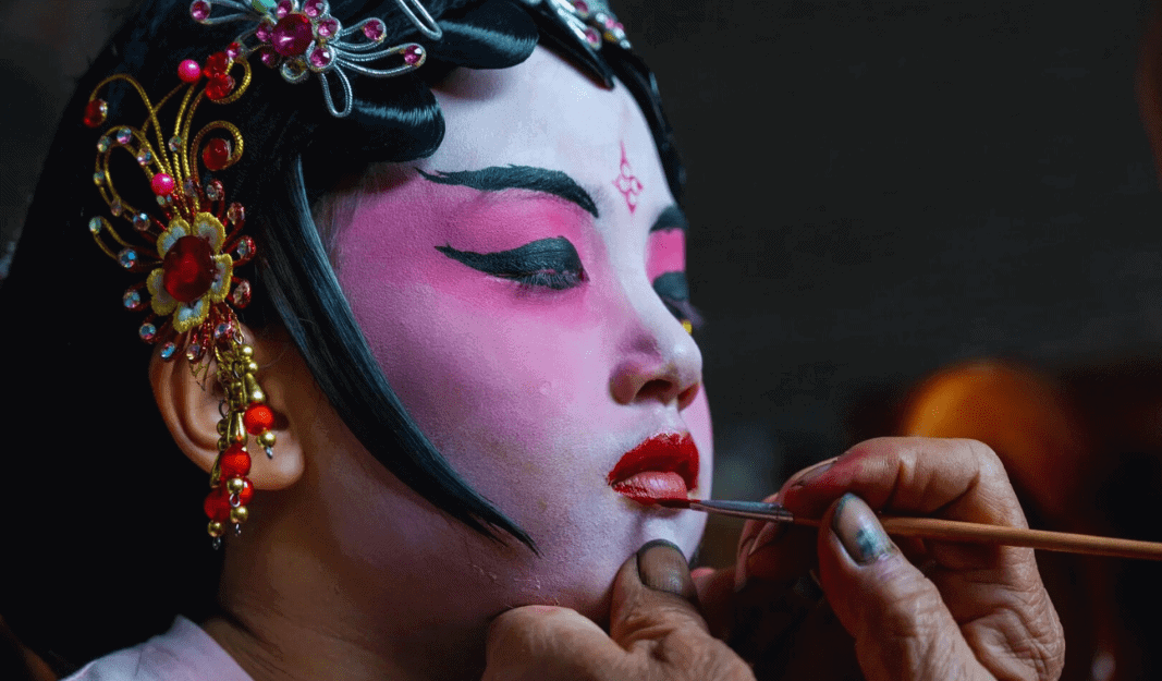 Young girl receiving face paint in preparation for the traditional Piaose parade in Taishan.