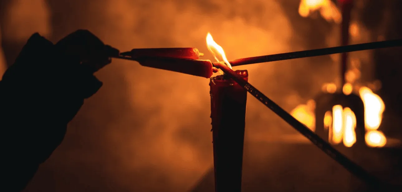 Lighting incense sticks from a candle flame during modern ancestor worship practices.