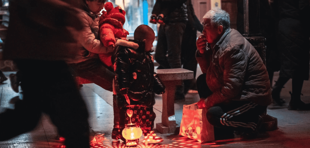 Family gathering around a glowing lantern, symbolizing modern ancestor worship practices in a communal setting.