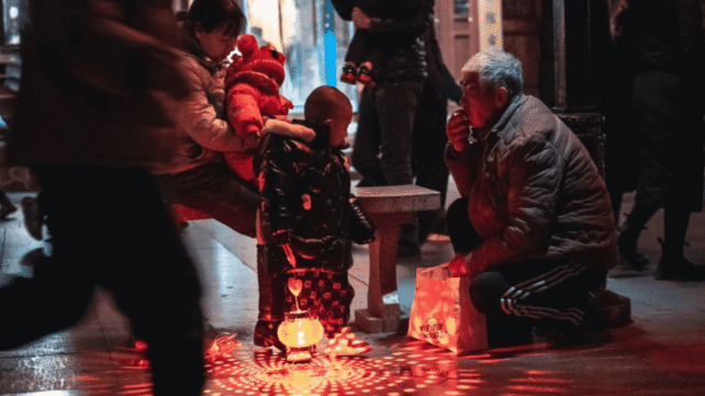 Family gathering around a glowing lantern, symbolizing modern ancestor worship practices in a communal setting.