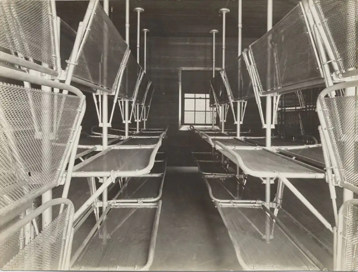 Period photograph of the Angel Island detention-barracks dormitory interior with rows of metal bunks, circa 1910s