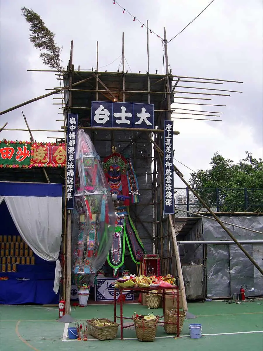 The towering Great Master effigy at a Yu Lan festival gathering, its fierce face presiding over rites for the wandering dead.