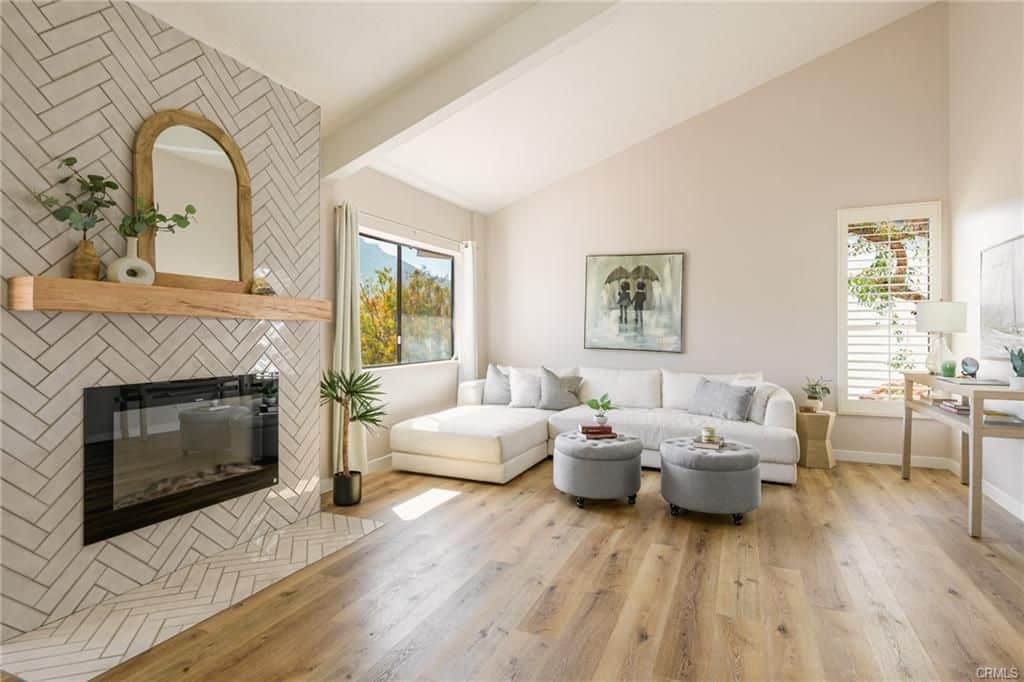 Living room with fireplace, white sectional sofa, and light wood flooring.