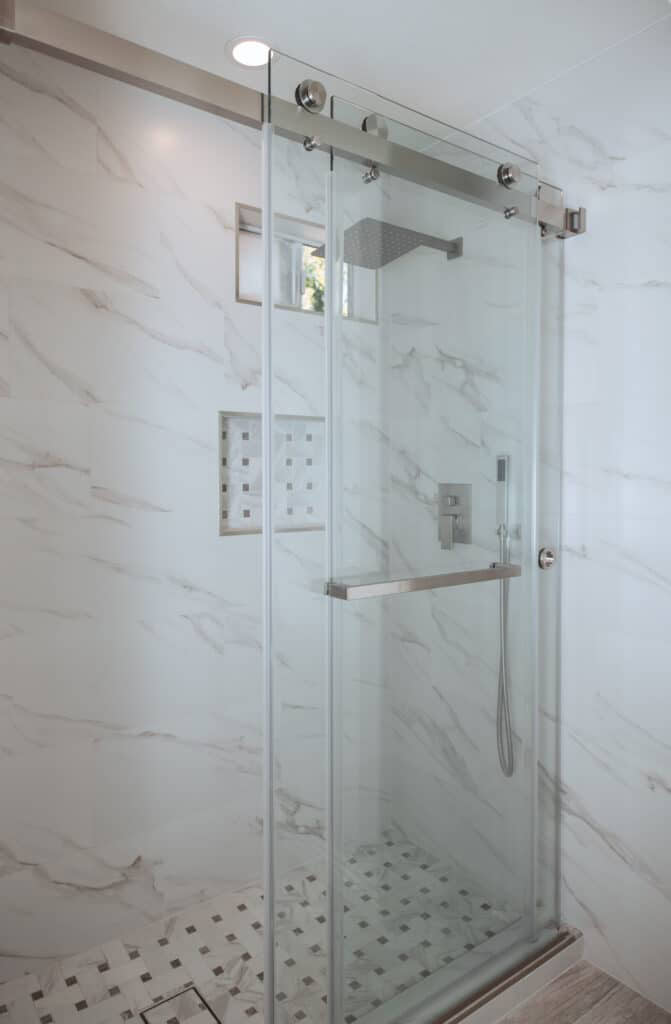 Modern glass shower with white marble walls and tiled floor