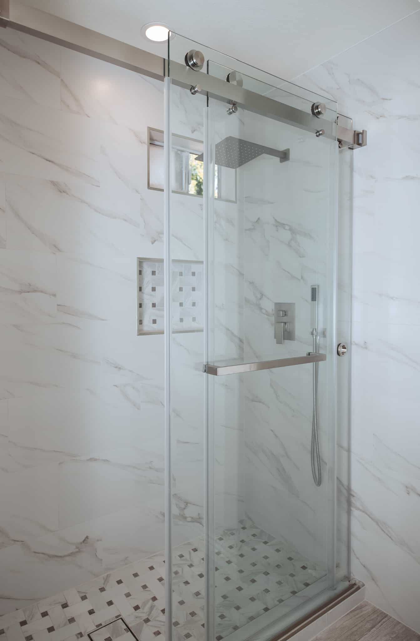 Modern glass shower with white marble walls and tiled floor