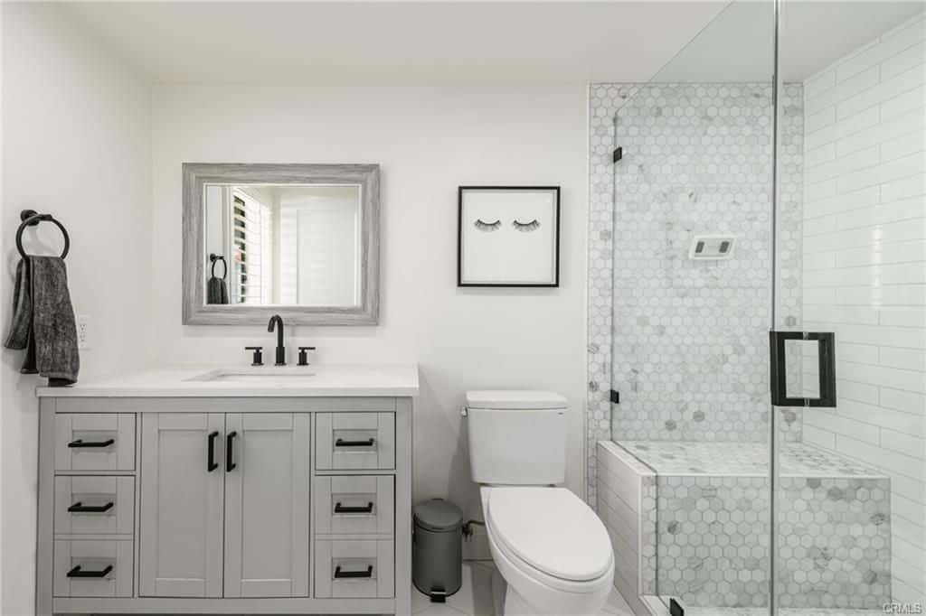 Modern bathroom with light gray vanity, white toilet, and glass shower.