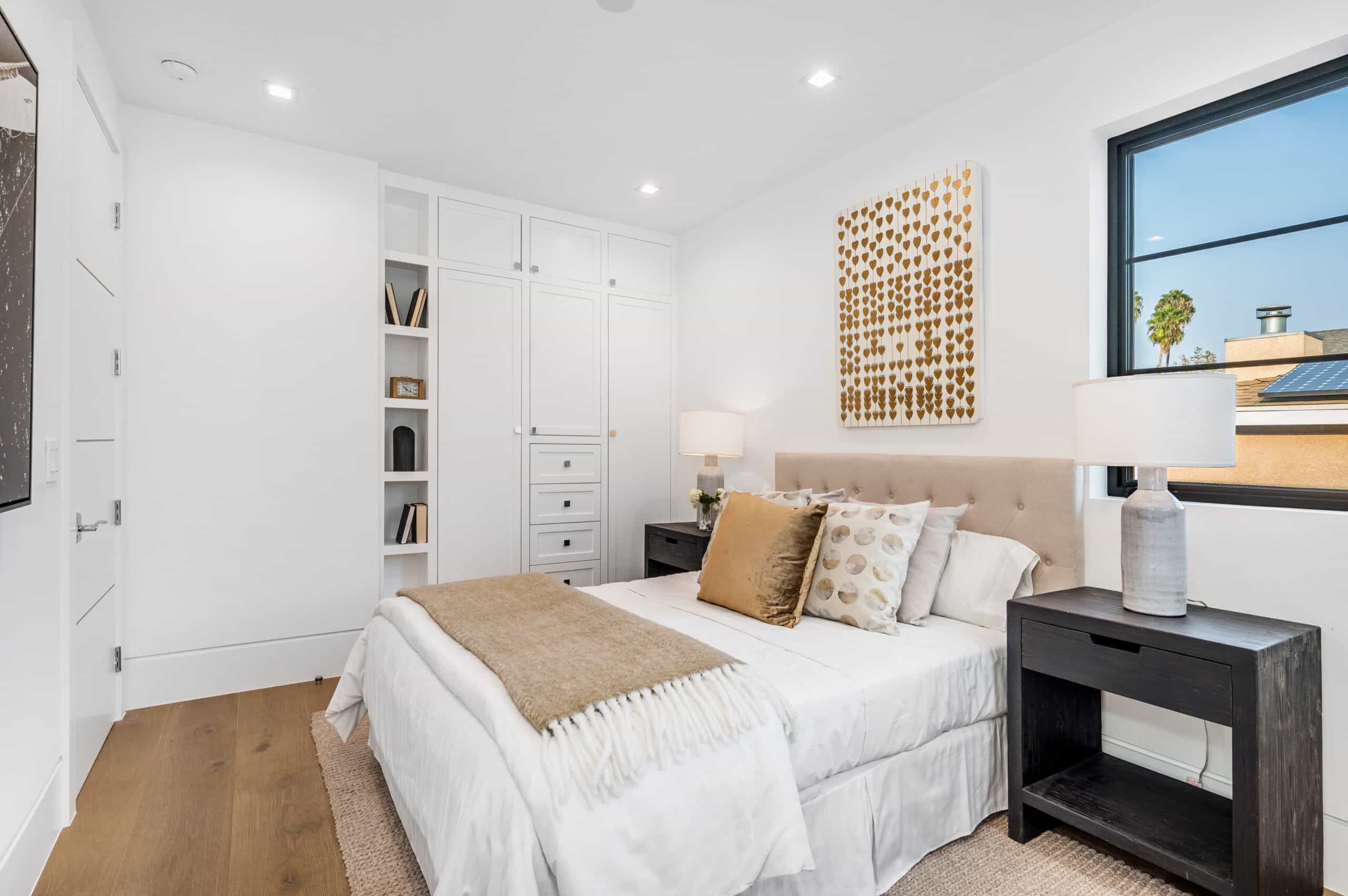 Bright bedroom with white walls, a bed, built-in wardrobe, and window.
