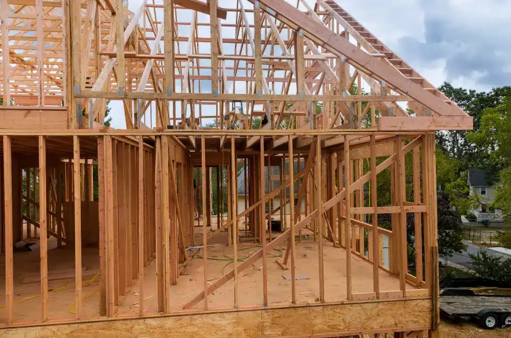Wooden framework of a house under construction against a cloudy sky.