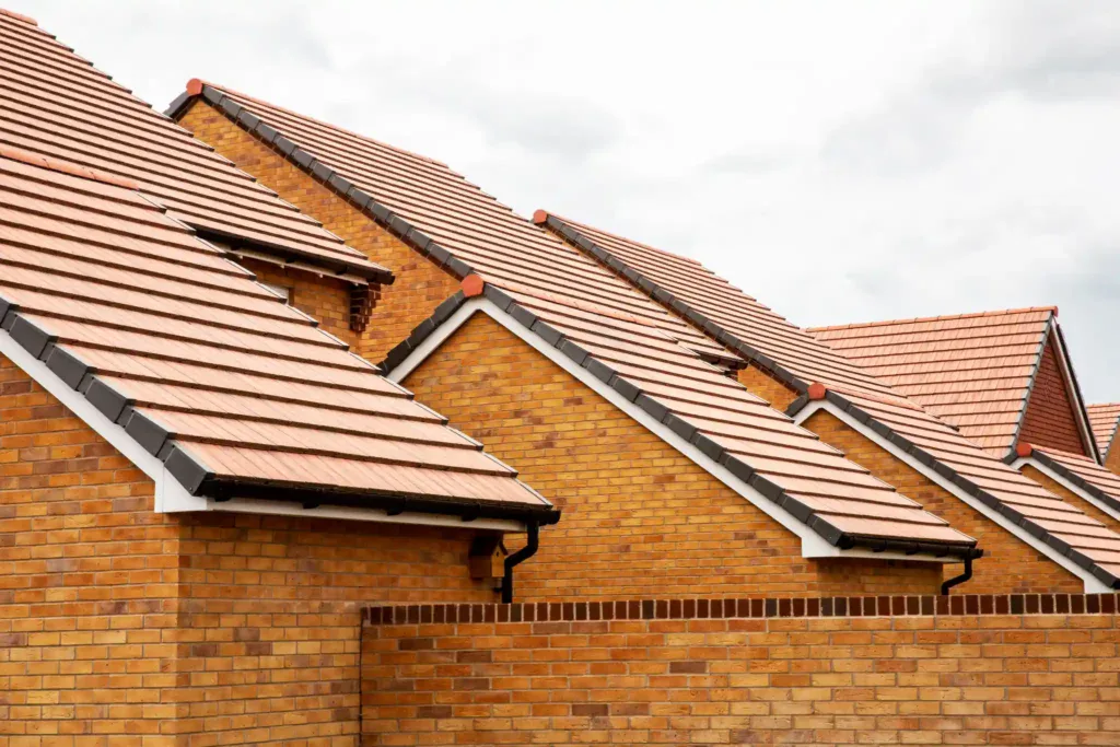 Close-up of new brick houses with red tiled roofs under a cloudy sky.