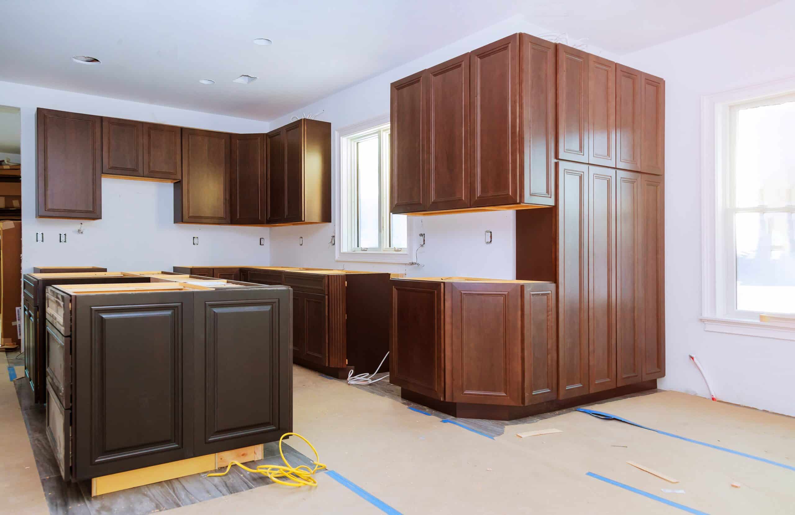 Kitchen under construction with dark wood cabinets and white walls