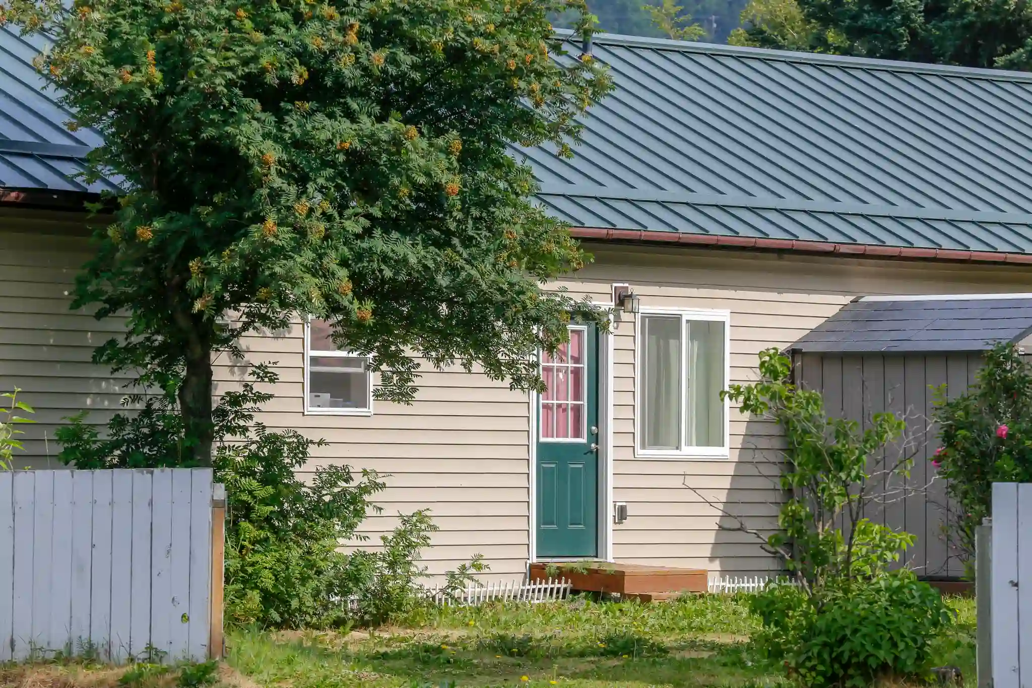 A beige house with a green door and a metal roof.