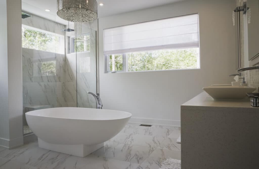 Modern bathroom with a freestanding tub, glass shower, and large window